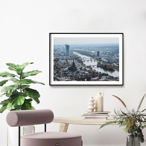 Frankfurt Bild im Querformat, Blick über die Stadt. Bild mit weißen umlaufenden Rand. Bild gerahmt an der Wand im Wohnzimmer.