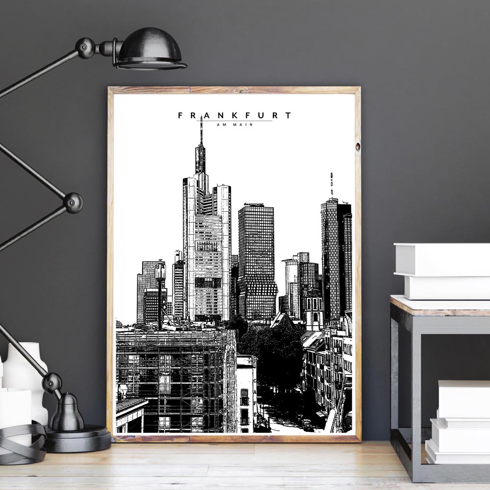 Illustration der Skyline von Frankfurt. Schwarz Weiß Poster gerahmt in einem hellen Bilderrahmen, der auf dem Boden an einer grauen Wand steht.