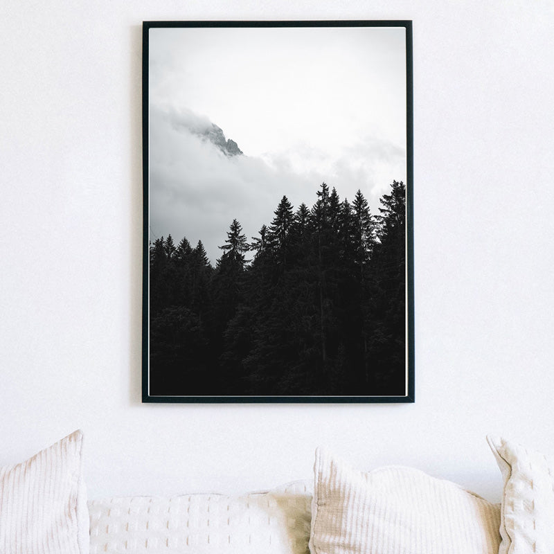 Schwarz Weiß Natur Poster über dem Sofa in einem schwarzen Bilderrahmen. Baum Kronen von einem Wald vor einem Berg.