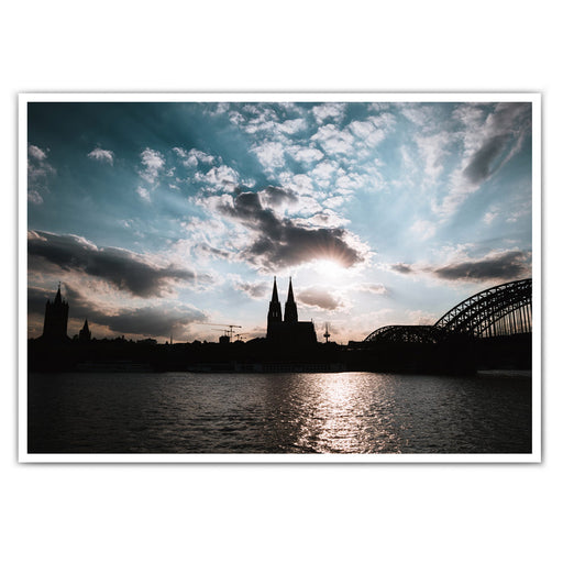 Köln Skyline Poster im Querformat. Sonnenuntergang über dem Kölner Dom bei leicht bewölkten blauen Himmel.