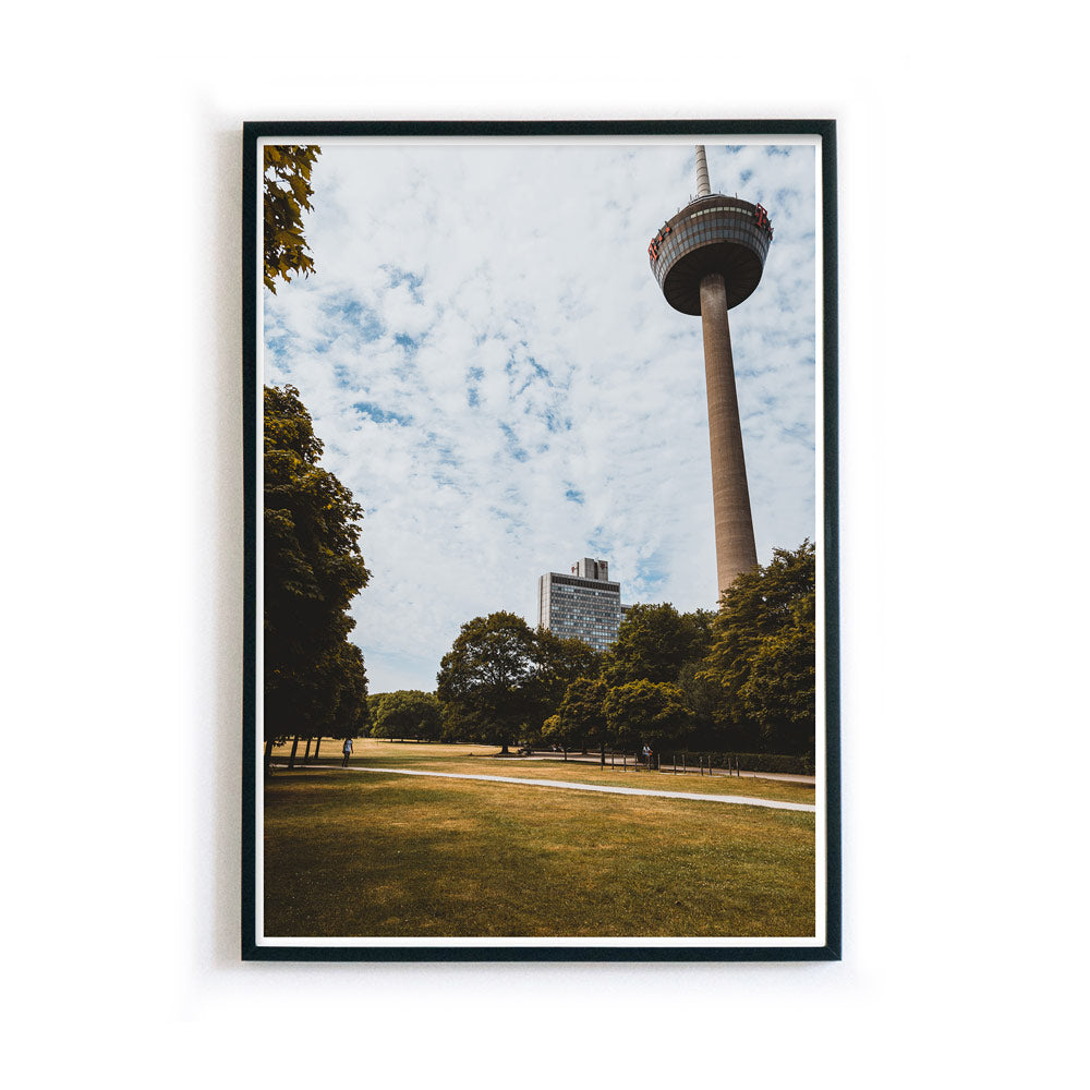 Retro Köln Poster vom Fernsehturm im grünen Gürtel. Grüne Wiese und Bäume im Vordergrund bei blauem bewölkten Himmel. Bild im Rahmen.