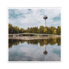 Köln Bild Quadratisch. Motiv ist der Fernsehturm, eine Brücke und Bäume, die sich im See spiegeln. Sommertag mit blauem Himmel.