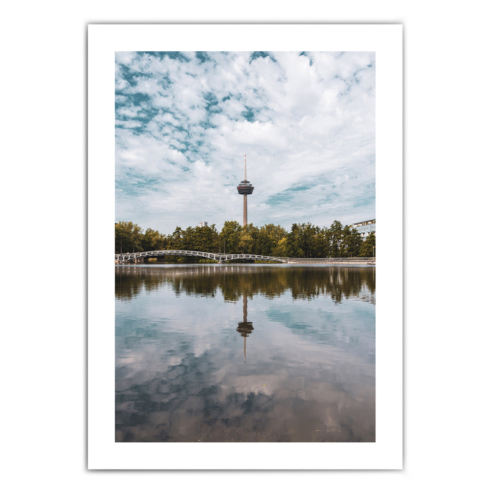 Sommer Köln Bild mit weißen Rand in Hochformat. Fernsehturm ist mittig im Bild und spiegelt sich im See im Vordergrund.