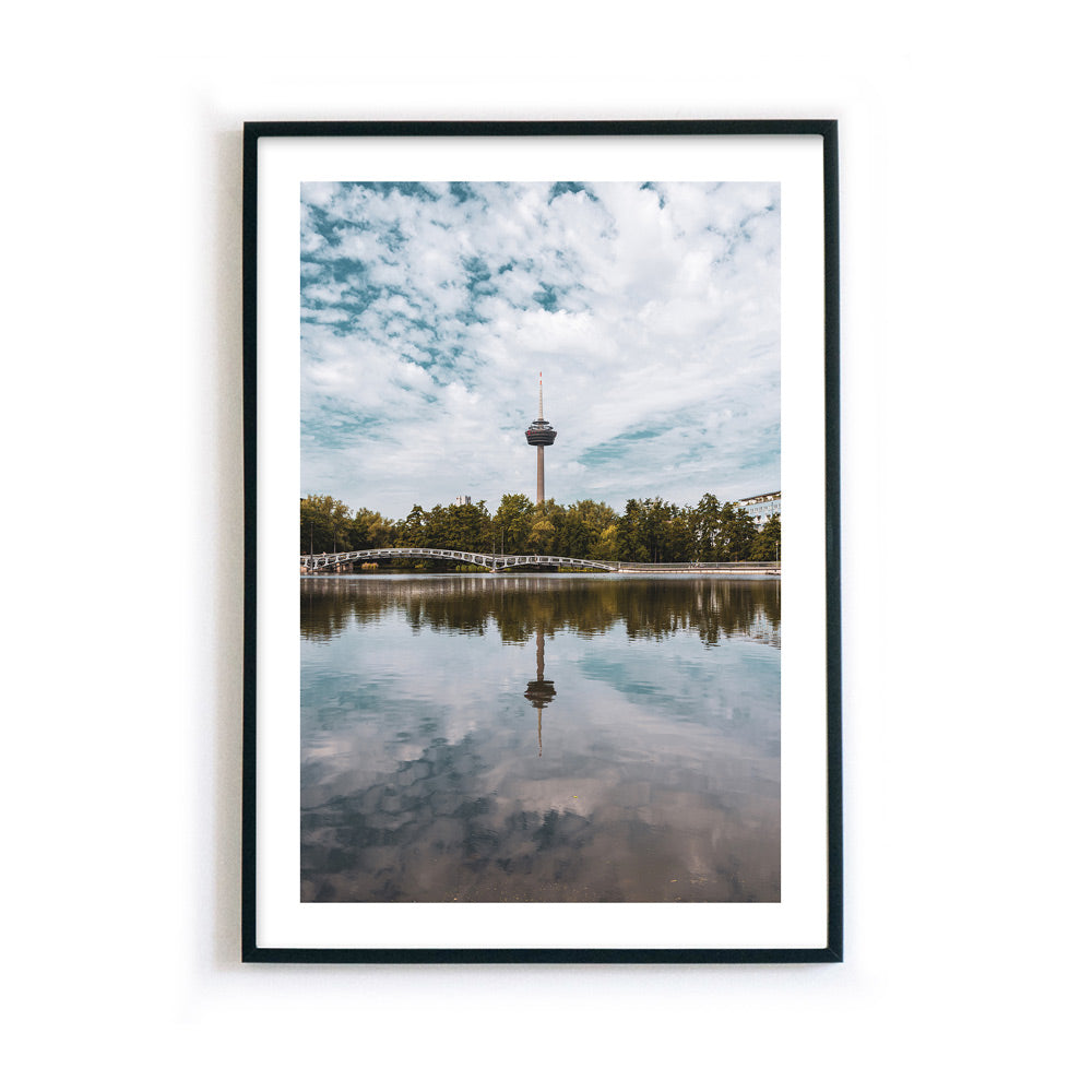 Sommer Köln Bild mit weißen Rand und Rahmen in Hochformat. Fernsehturm ist mittig im Bild und spiegelt sich im See im Vordergrund.